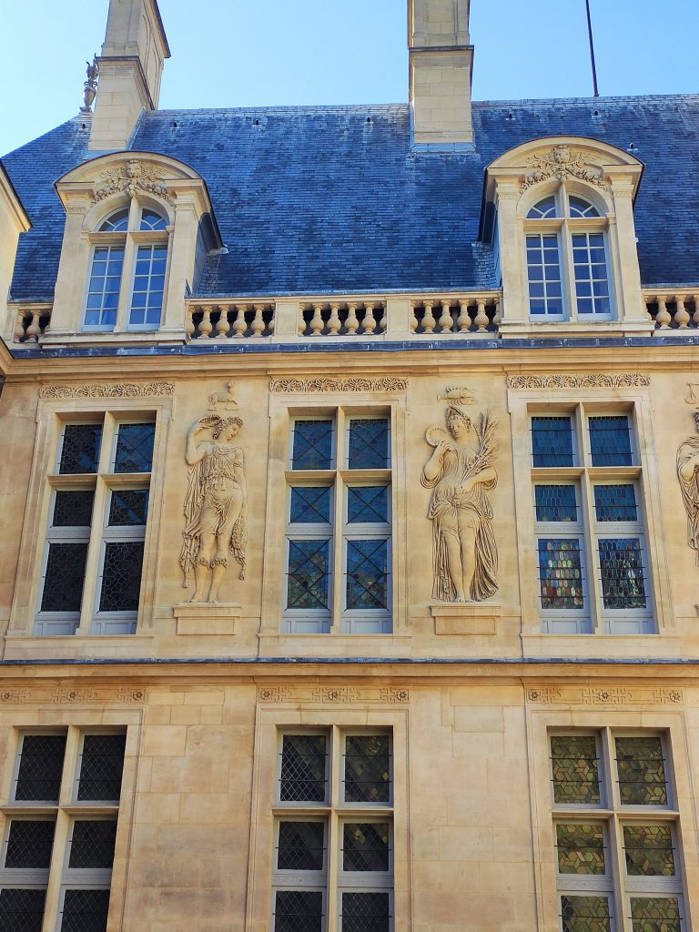 Façade de cour du Musée Carnavalet à Paris avec des reliefs sculptés entre les fenêtres