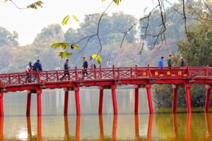 Des piétons traversent le joli vieux pont rouge en bois de Hoi An (Vietnam)