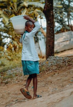 Un enfant dans un pays africain portant un seu de céréales à l'épaule