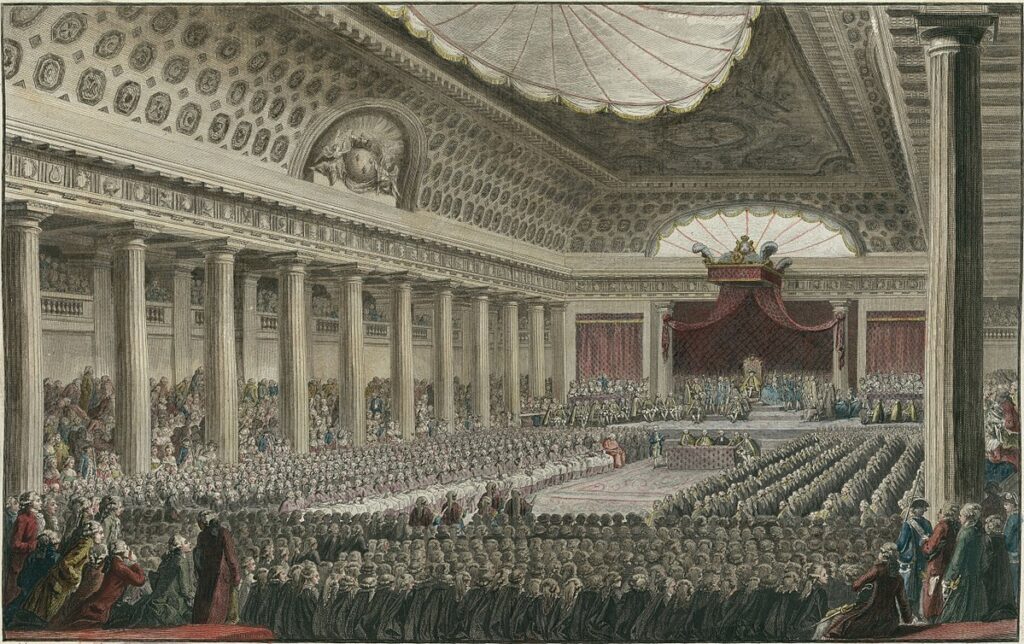 Dans une grande salle à colonnade, des centaines de délégués réunis pour les états généraux regardent vers l'estrade où se tient le roi Louis XVI