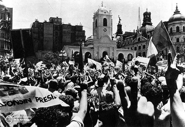 Sur une place de Buenos Aires, une foule agite des drapeaux et banderoles pour saluer l'élection de Raul Alfonsin