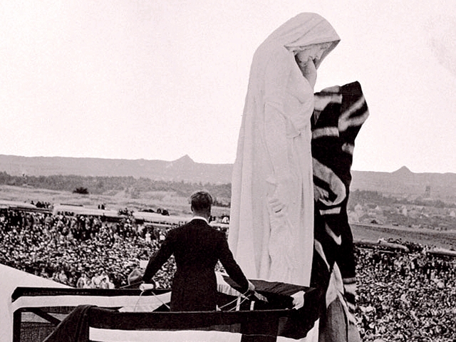 Photo noir et blanc : lors de l'inauguration du monument de la Première Guerre Mondiale à Vimy, devant une foule dans un paysage du nord de la France, le roi britannique Edward VIII est vu de dos au pied d'une grande statue qui représente le Canada