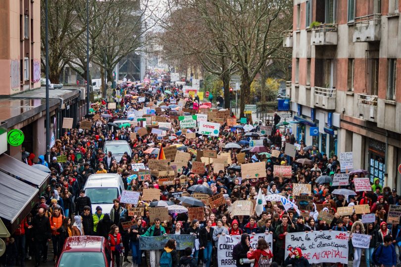 Manifestation pour la sauvegarde du climat ; une foule dense avec des pancartes défile calmement dans une rue d'une ville française