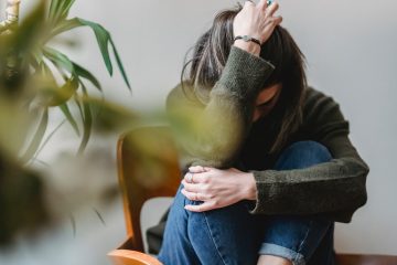 Une jeune femme atterrée par la détresse se recroqueville sur une chaise, le visage caché par le bras